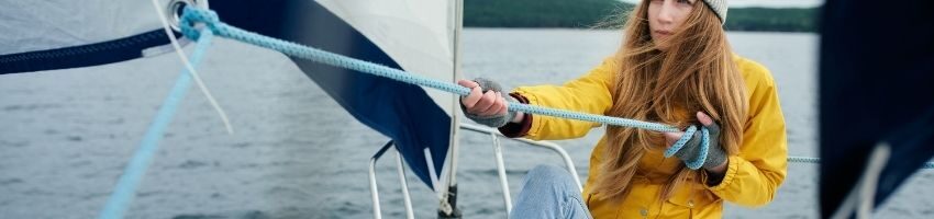 Young woman wearing yellow long sleeve trying to pull the rope in a small boat