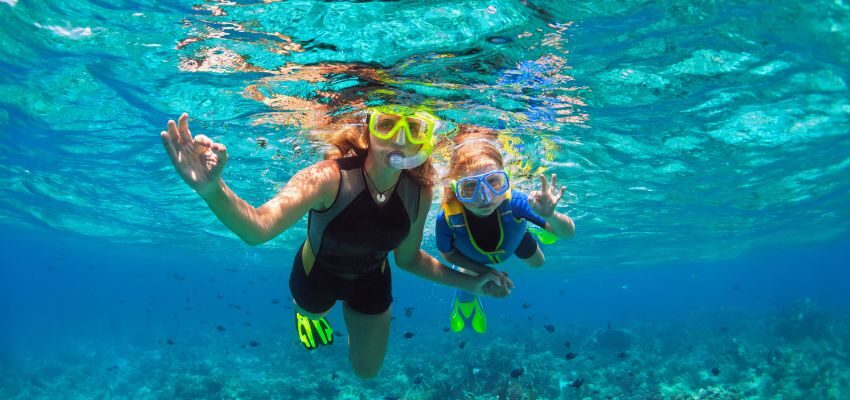 The mother and daughter are snorkeling in the Caribbean.